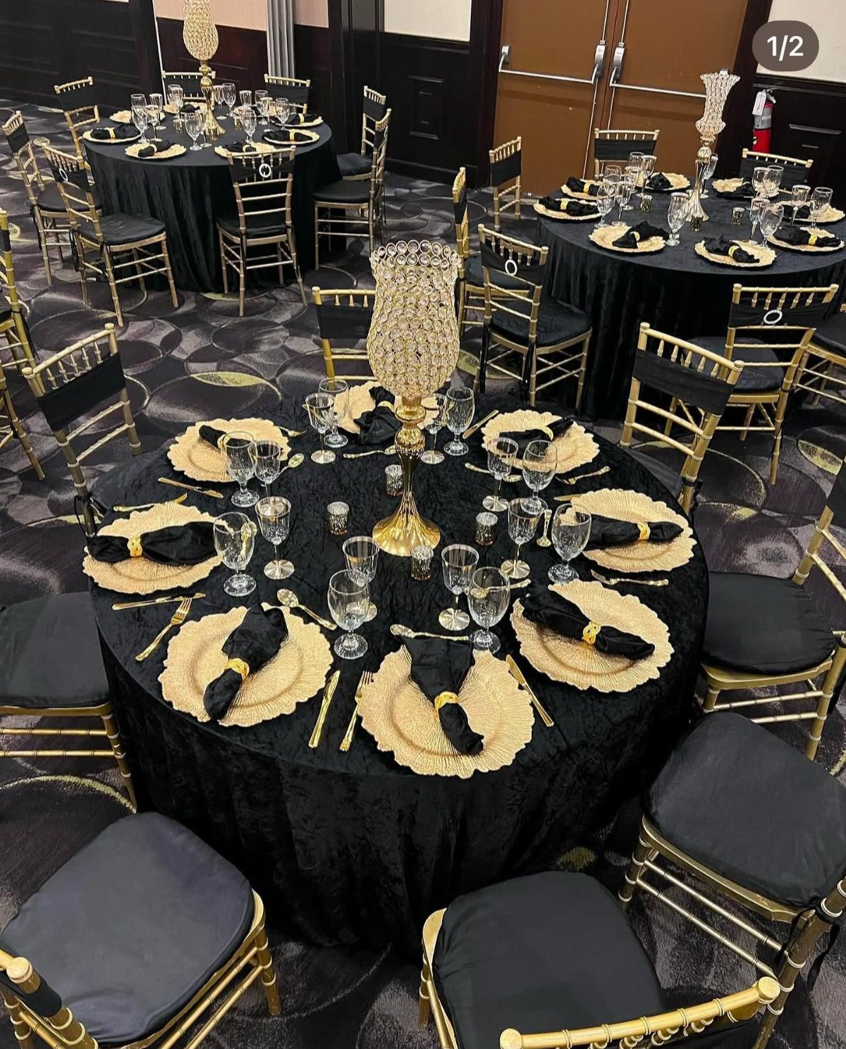 Formal banquet tables set with black linens, gold chargers, and tall crystal centerpieces.