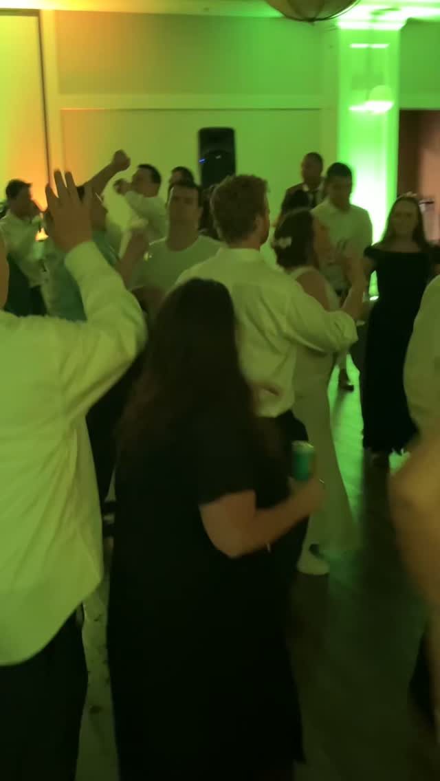 People dancing together in a room filled with vibrant green and yellow party lighting.