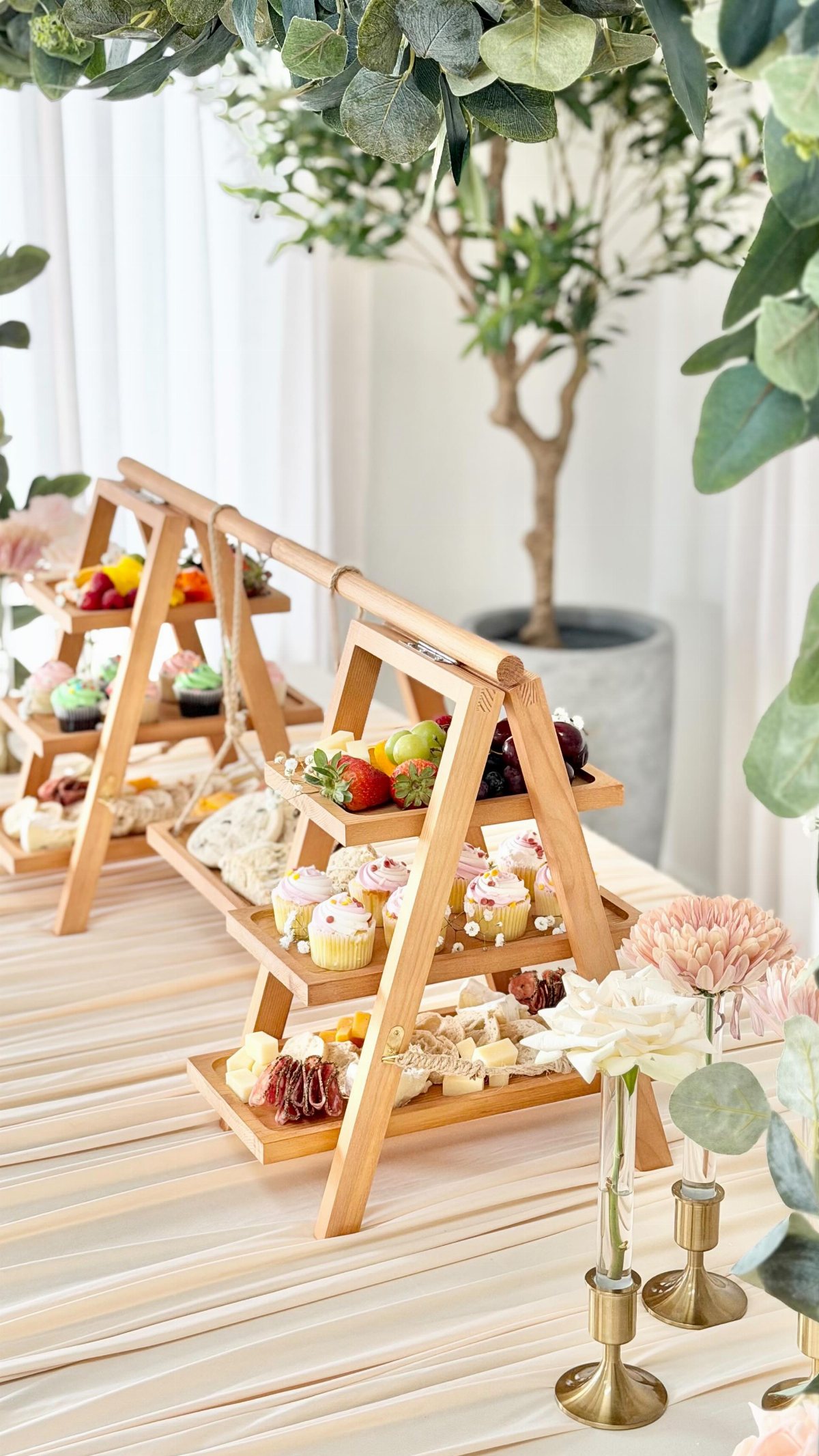 Tiered bamboo stands filled with assorted miniature fruit tarts and pastries on a table.