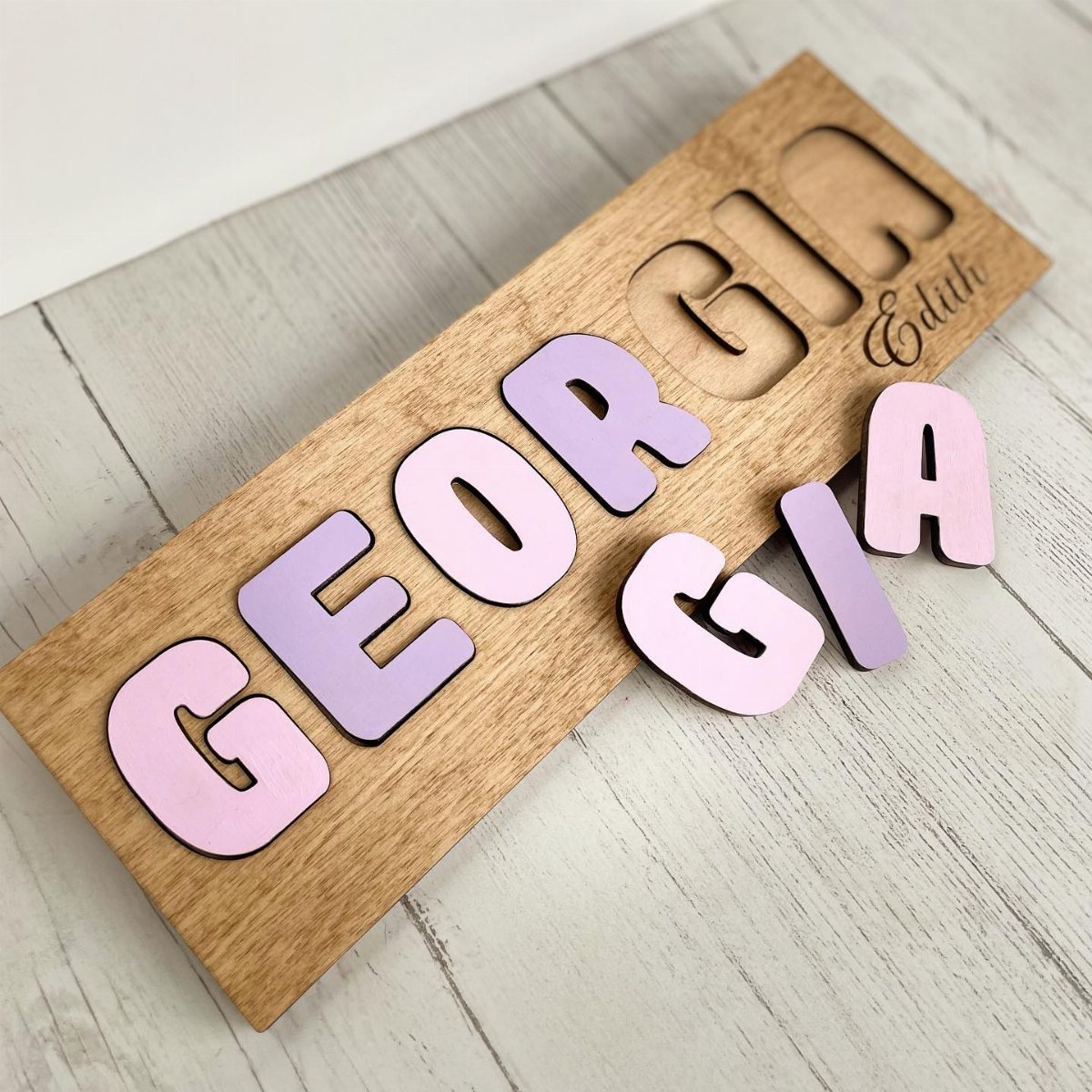 Pastel wooden letters spelling Georgia scattered over a custom wooden name plaque.