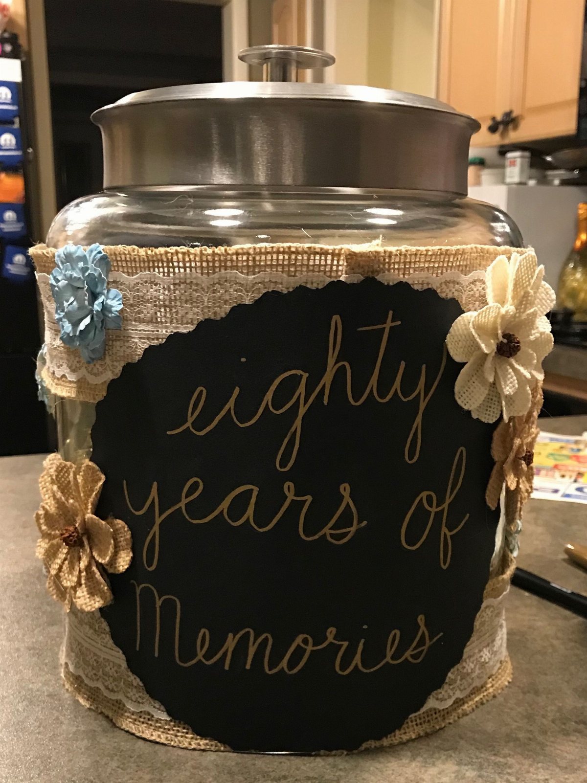 A decorated glass jar with a chalkboard sign that says eighty years of Memories.