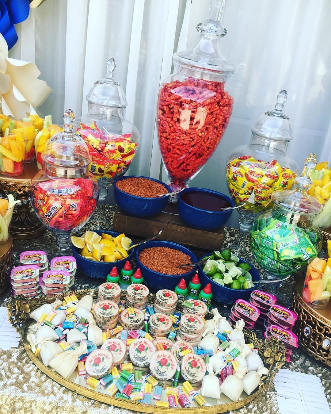 A vibrant candy bar table featuring glass jars filled with colorful sweets and bowls of toppings.