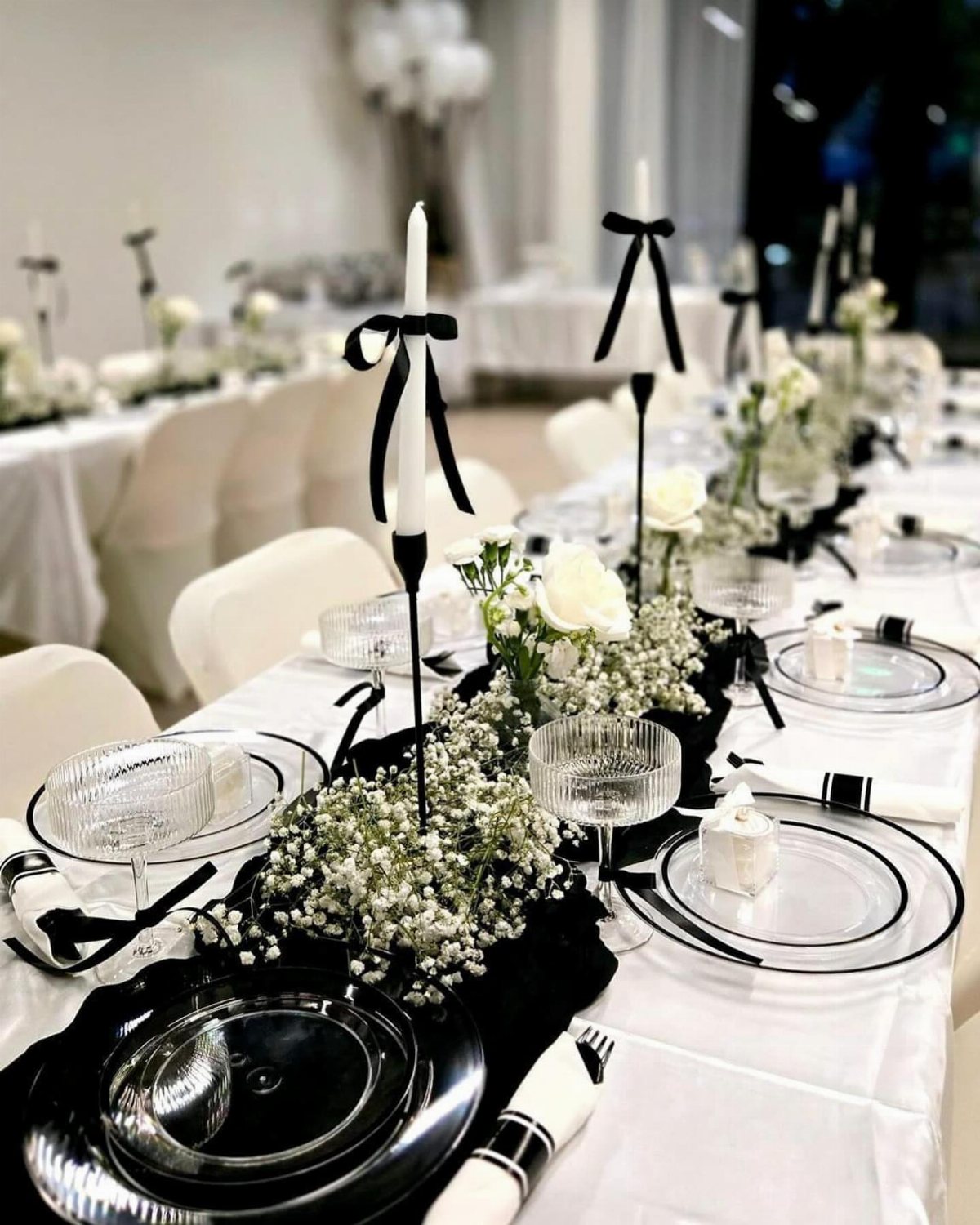 13 Black and White Wedding Decor Ideas for an Elegant Celebration 1 Wedding table setting featuring white flowers, black runners, and black candleholders with white taper candles.