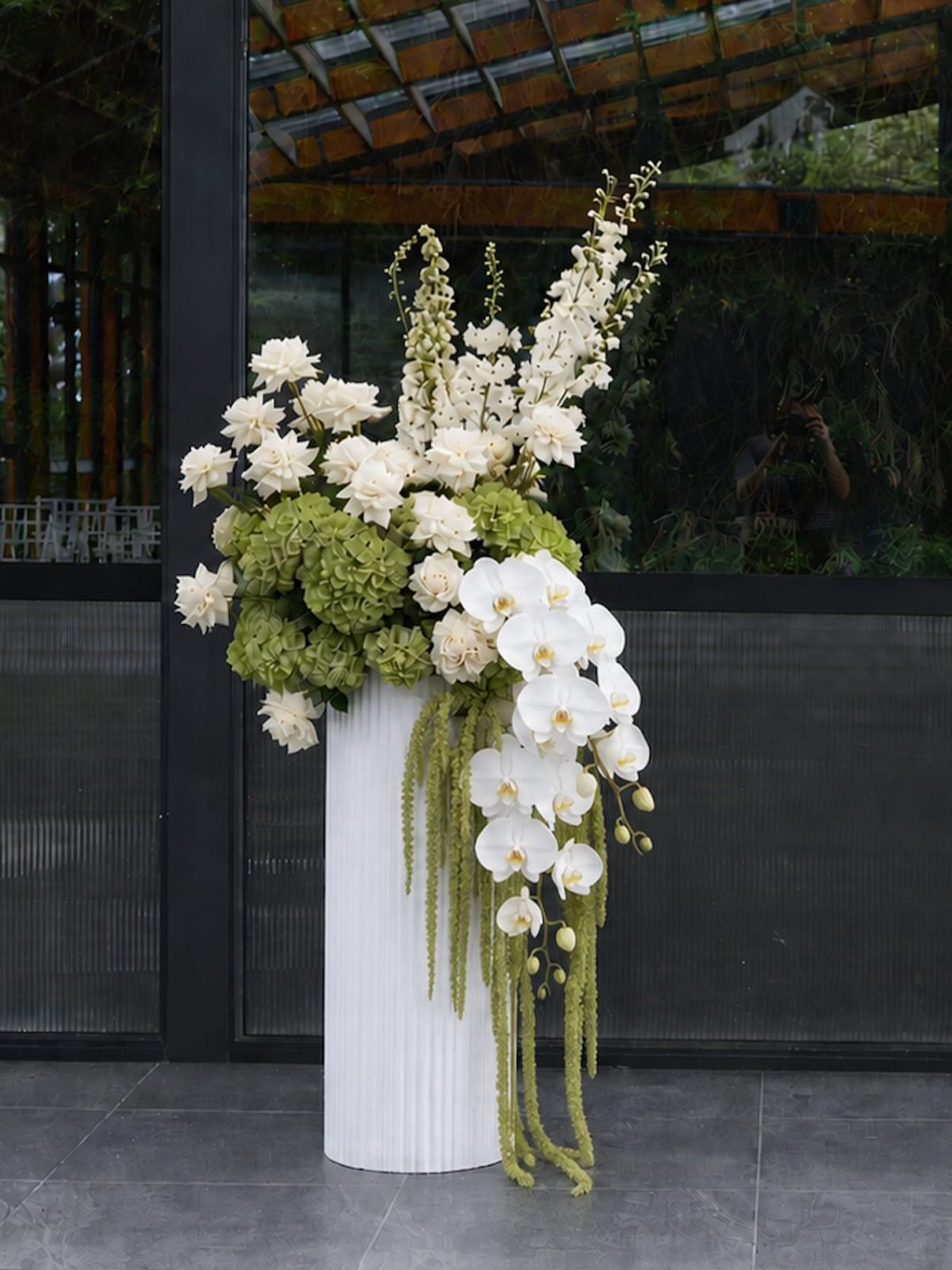 13 Black and White Wedding Decor Ideas for an Elegant Celebration 6 White orchids and roses arranged with green hydrangeas in a tall white fluted vase.
