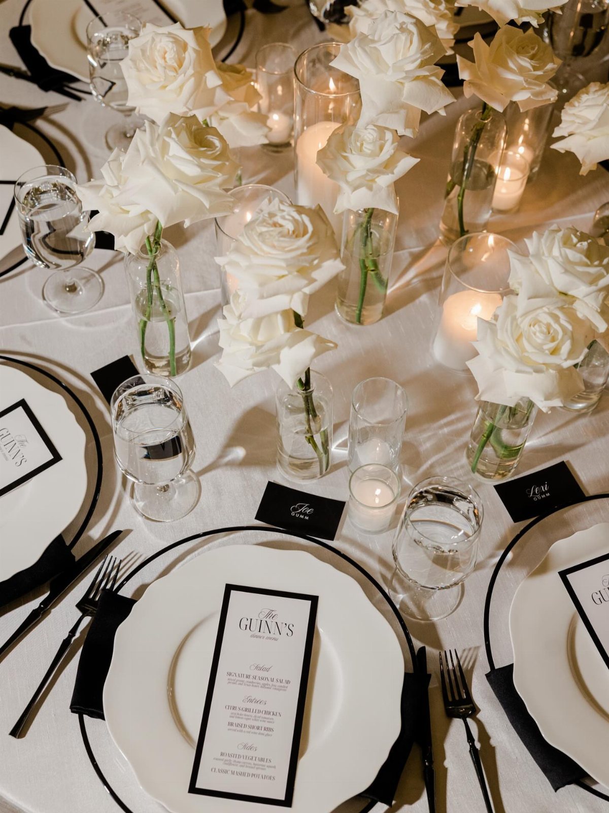 13 Black and White Wedding Decor Ideas for an Elegant Celebration 11 White roses and lit candles arranged on a wedding table with white tablecloths and black accents.
