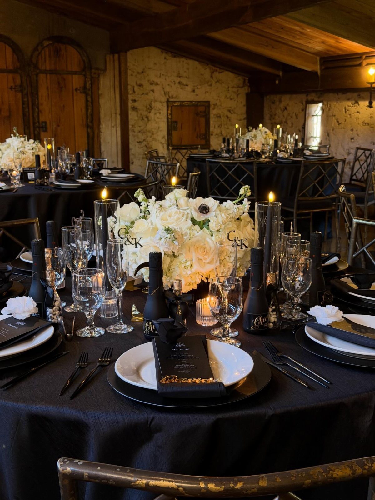 13 Black and White Wedding Decor Ideas for an Elegant Celebration 8 A formal dining table set with black linens, white plates, and white floral centerpieces.