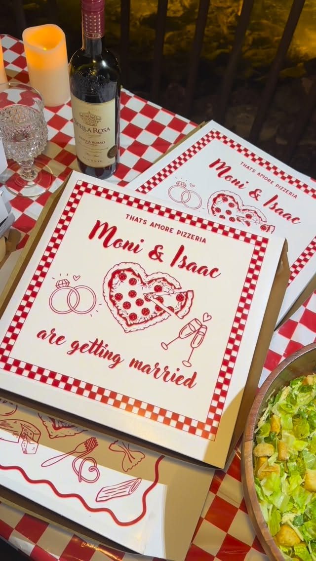 Customized pizza boxes with wedding announcements resting on a red and white checkered tablecloth.