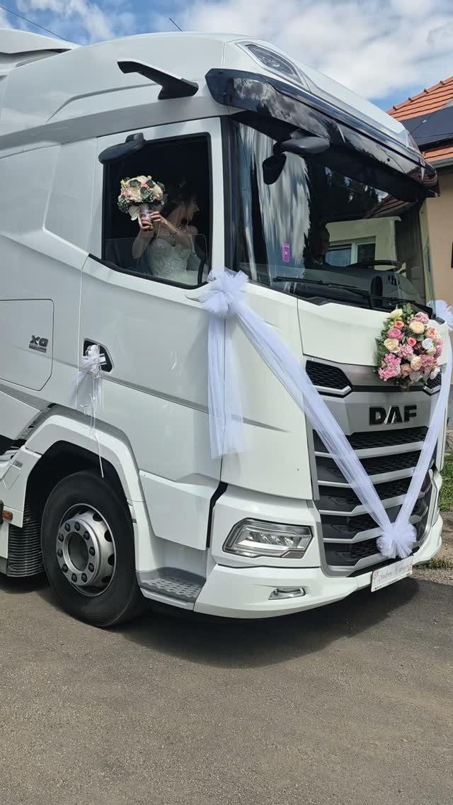 White semi-truck decorated with white tulle and pink floral bouquets for a wedding celebration.