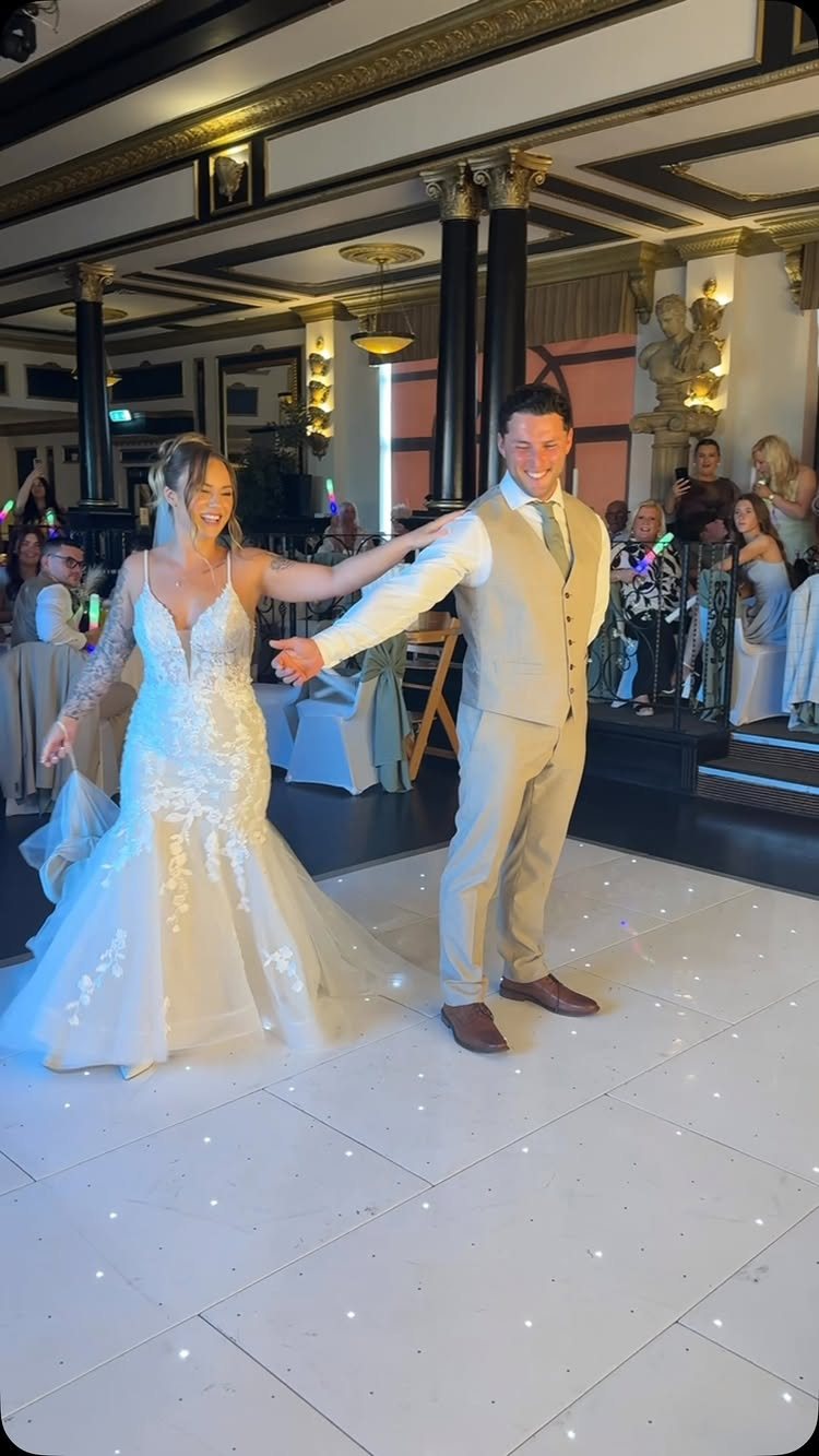 Bride and groom dancing together on a white illuminated dance floor in a ballroom.