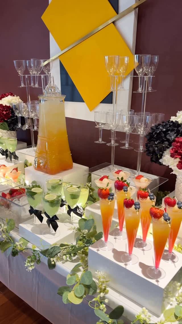 Colorful fruit-garnished mocktails arranged on white stands at a catered event.