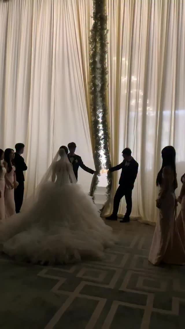 A bride and groom walking together through a curtained entrance during a wedding ceremony.
