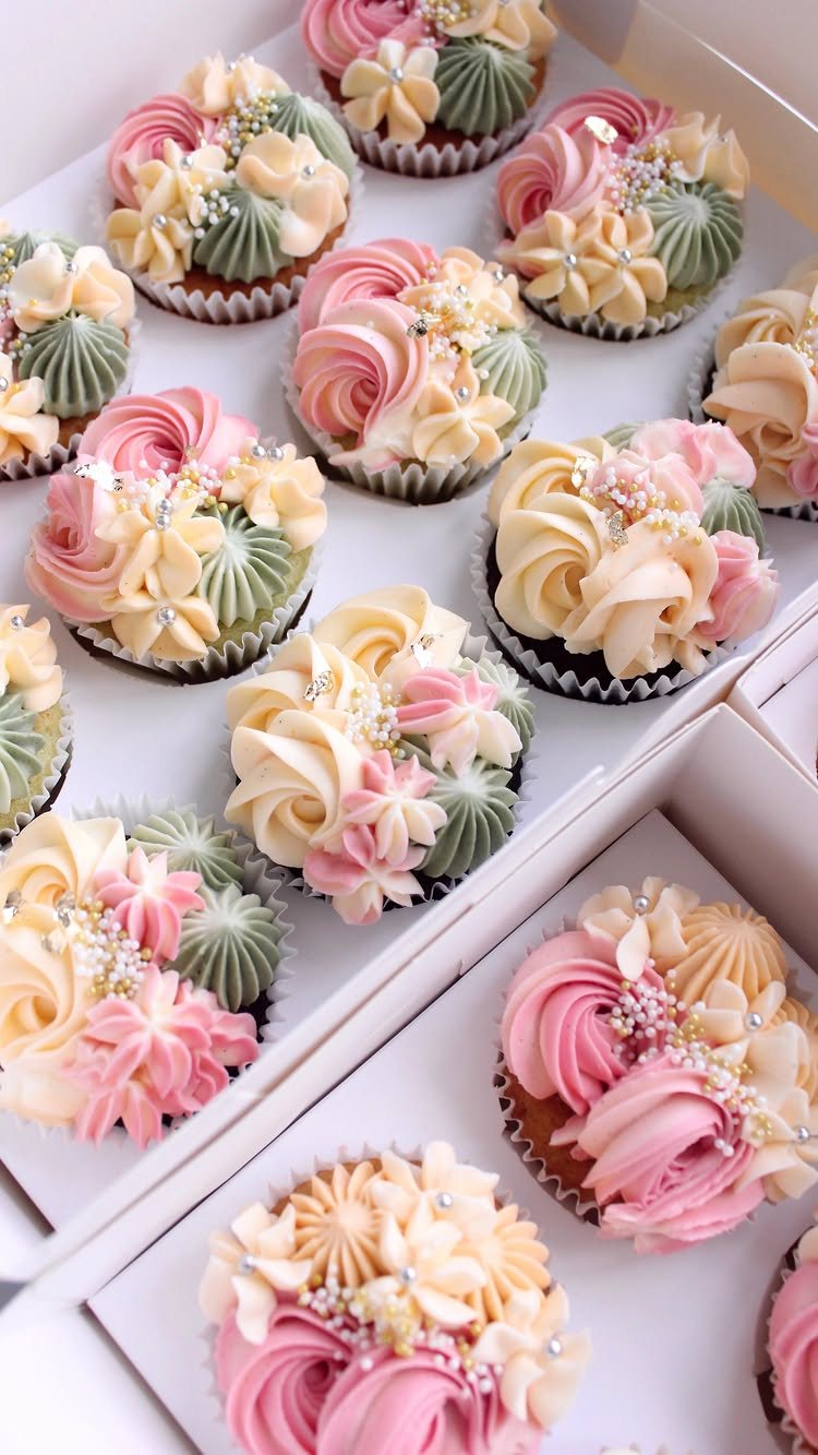 Cupcakes with pink, cream, and green buttercream frosting decorated with small white pearl sprinkles.