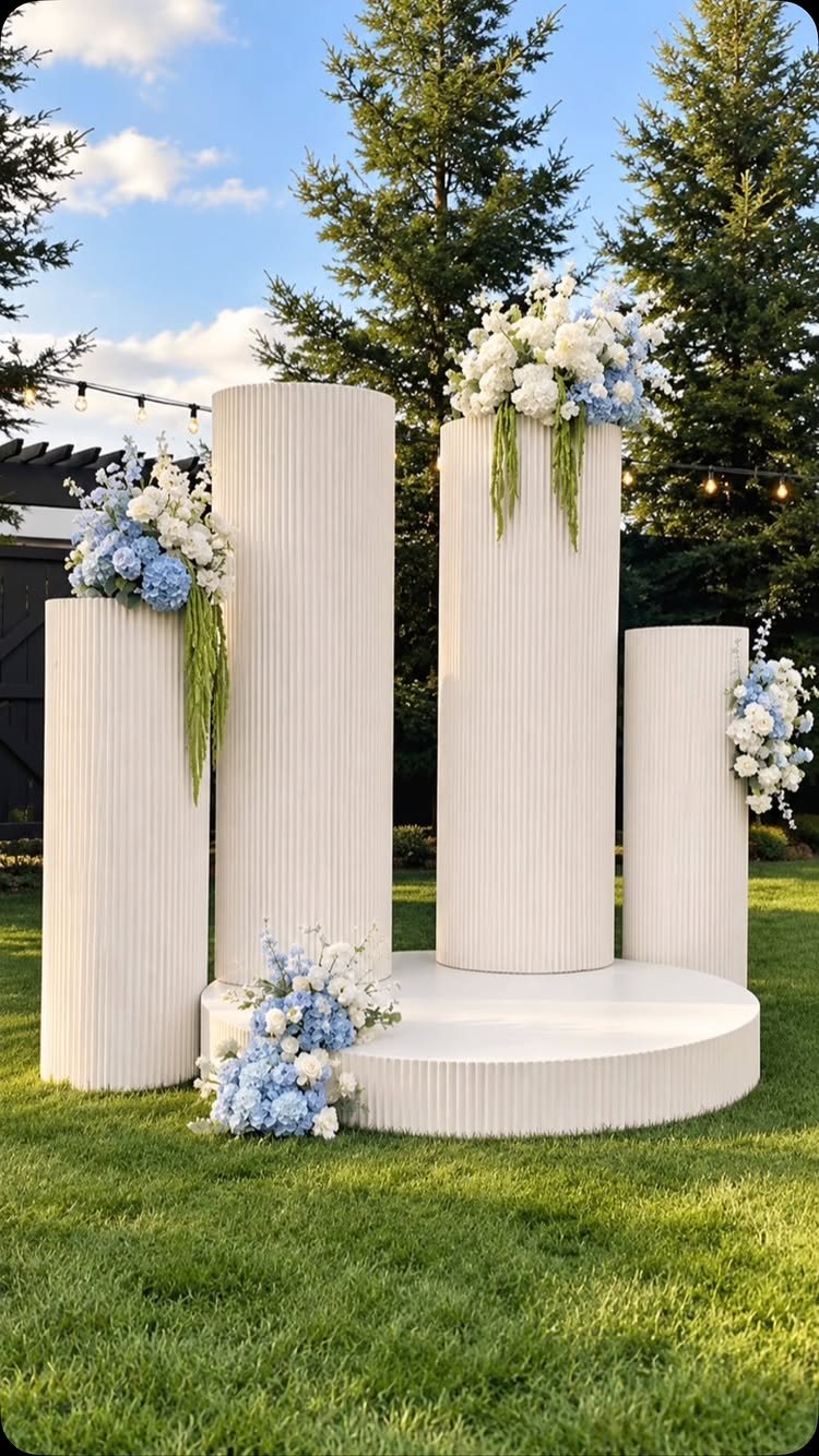 White fluted columns decorated with blue and white flowers on a circular platform outdoors.