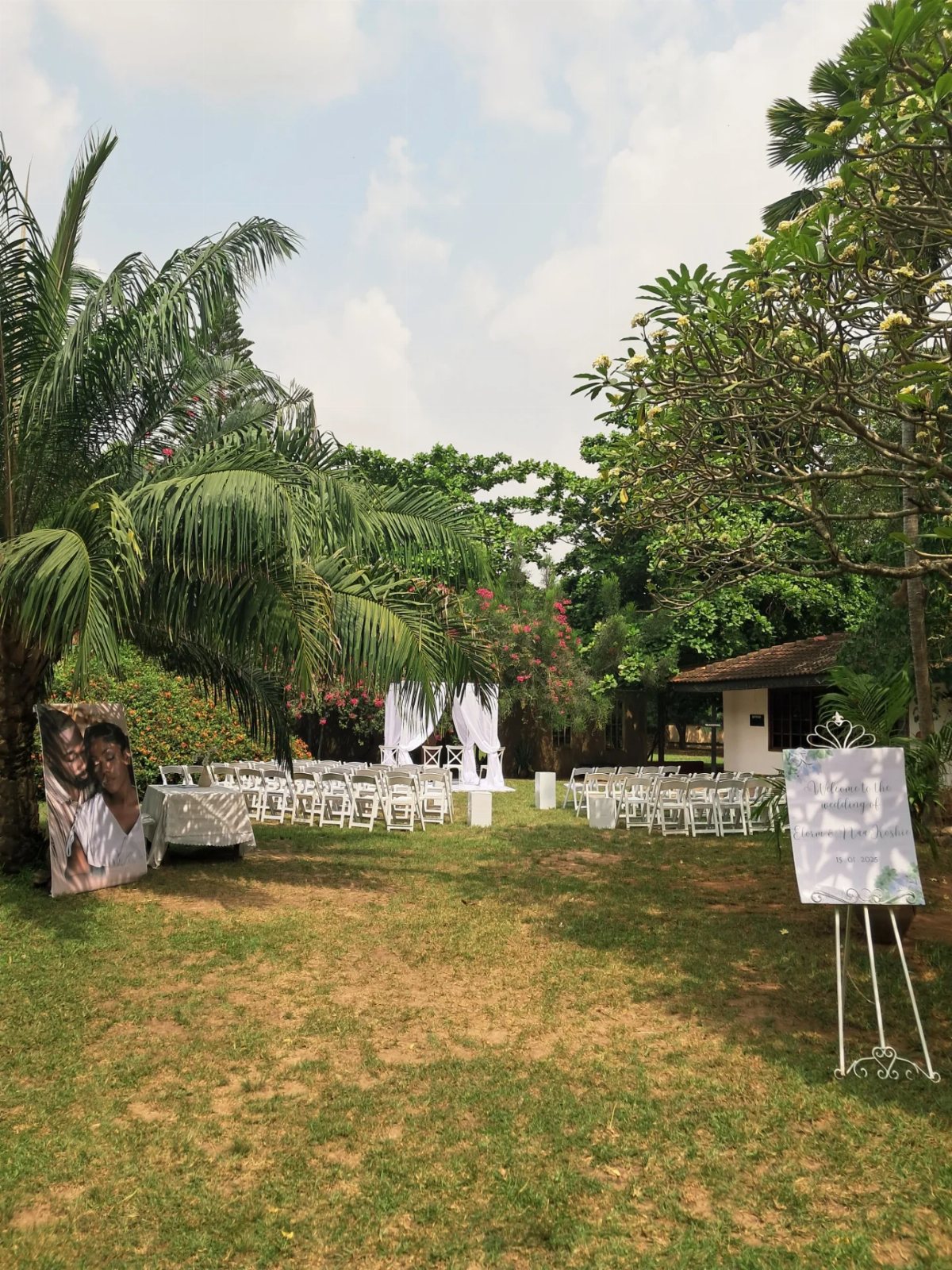 Outdoor wedding ceremony setup with white chairs and a draped altar on a green lawn.