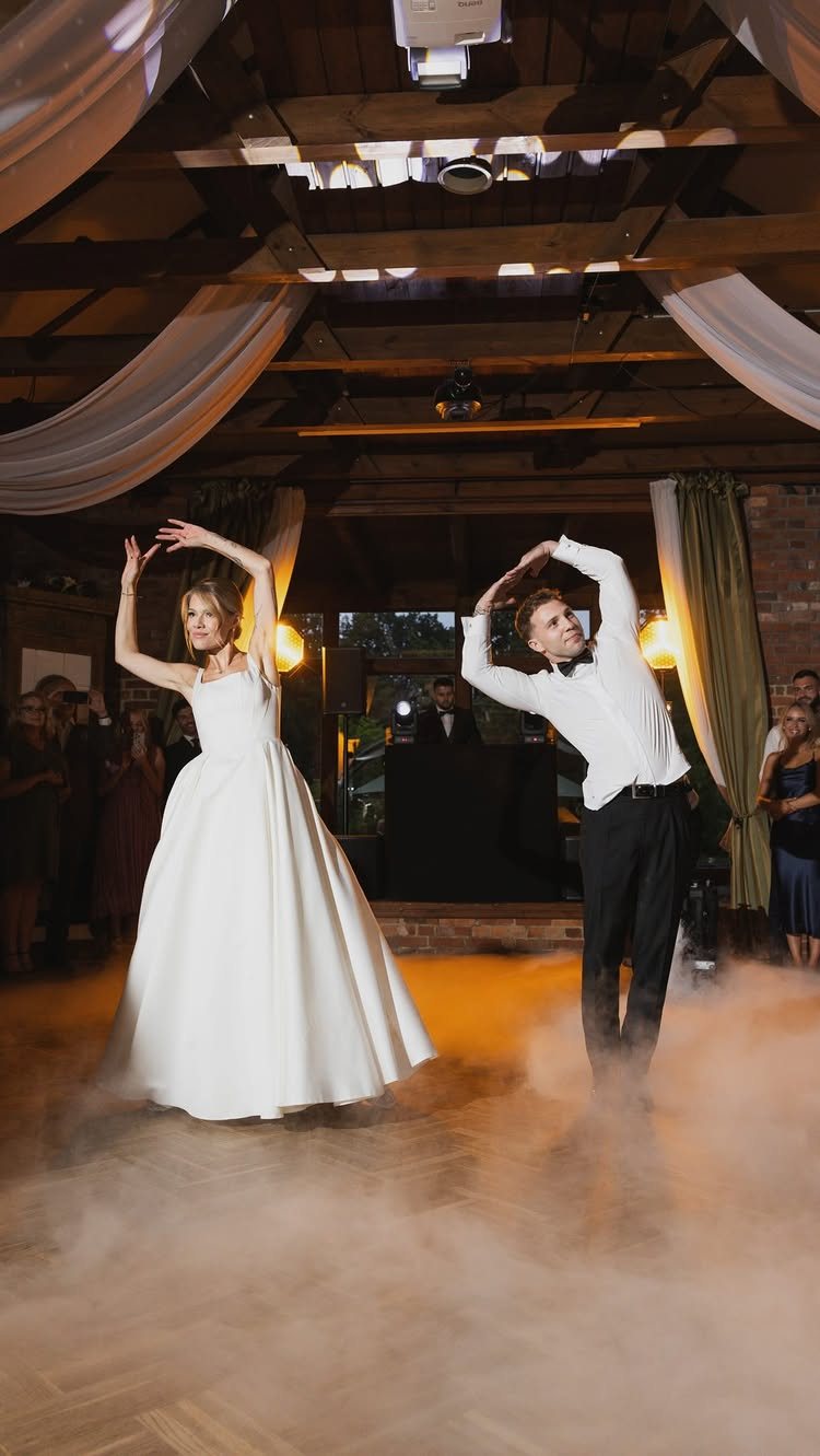 Bride and groom dancing on a foggy floor during their wedding reception.