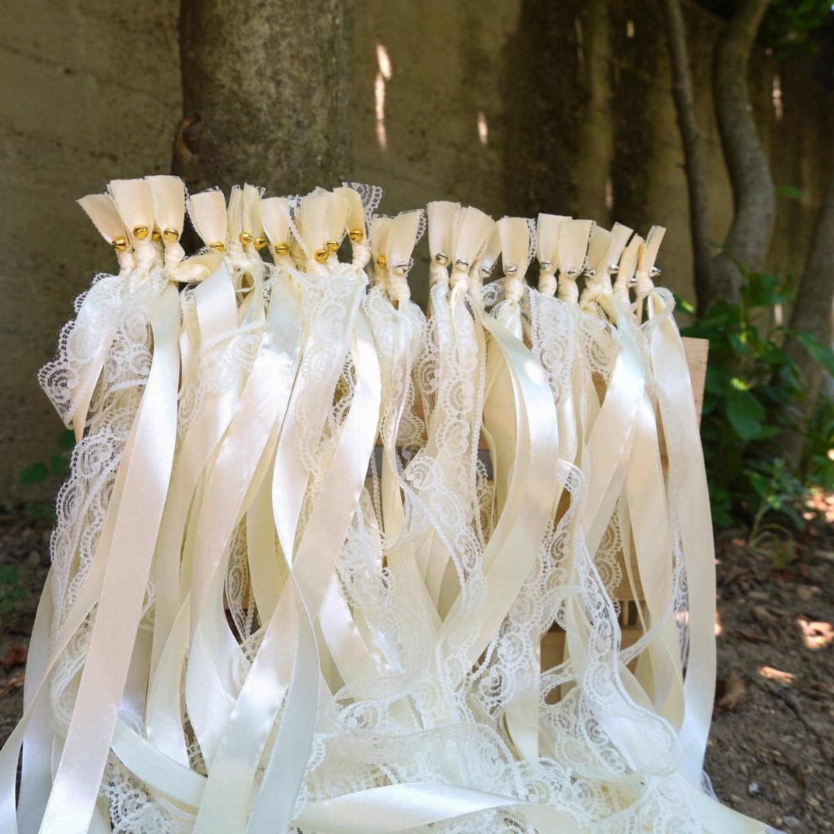 White satin and lace ribbon wands arranged together in an outdoor setting.