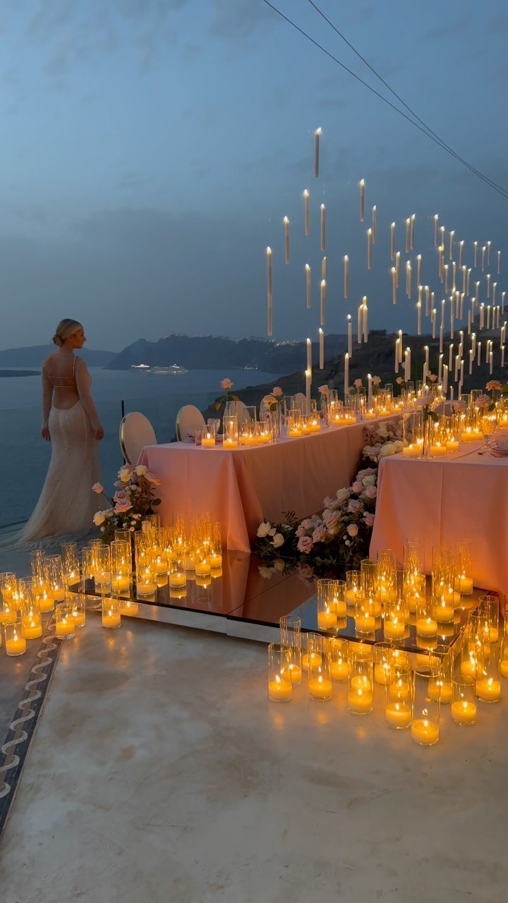 Numerous glowing candles on the floor and suspended in the air at an outdoor wedding reception.