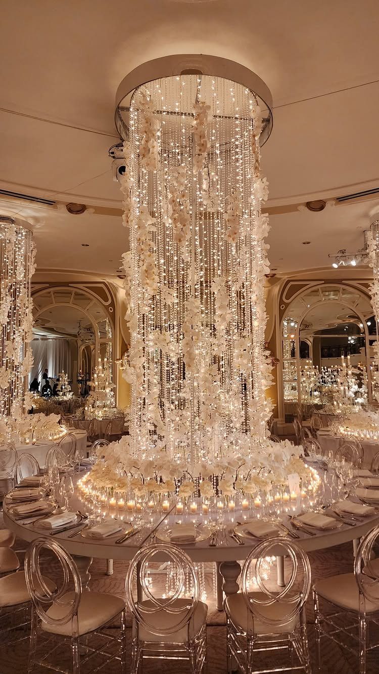 A massive crystal and floral centerpiece cascading from the ceiling onto a candlelit dining table.
