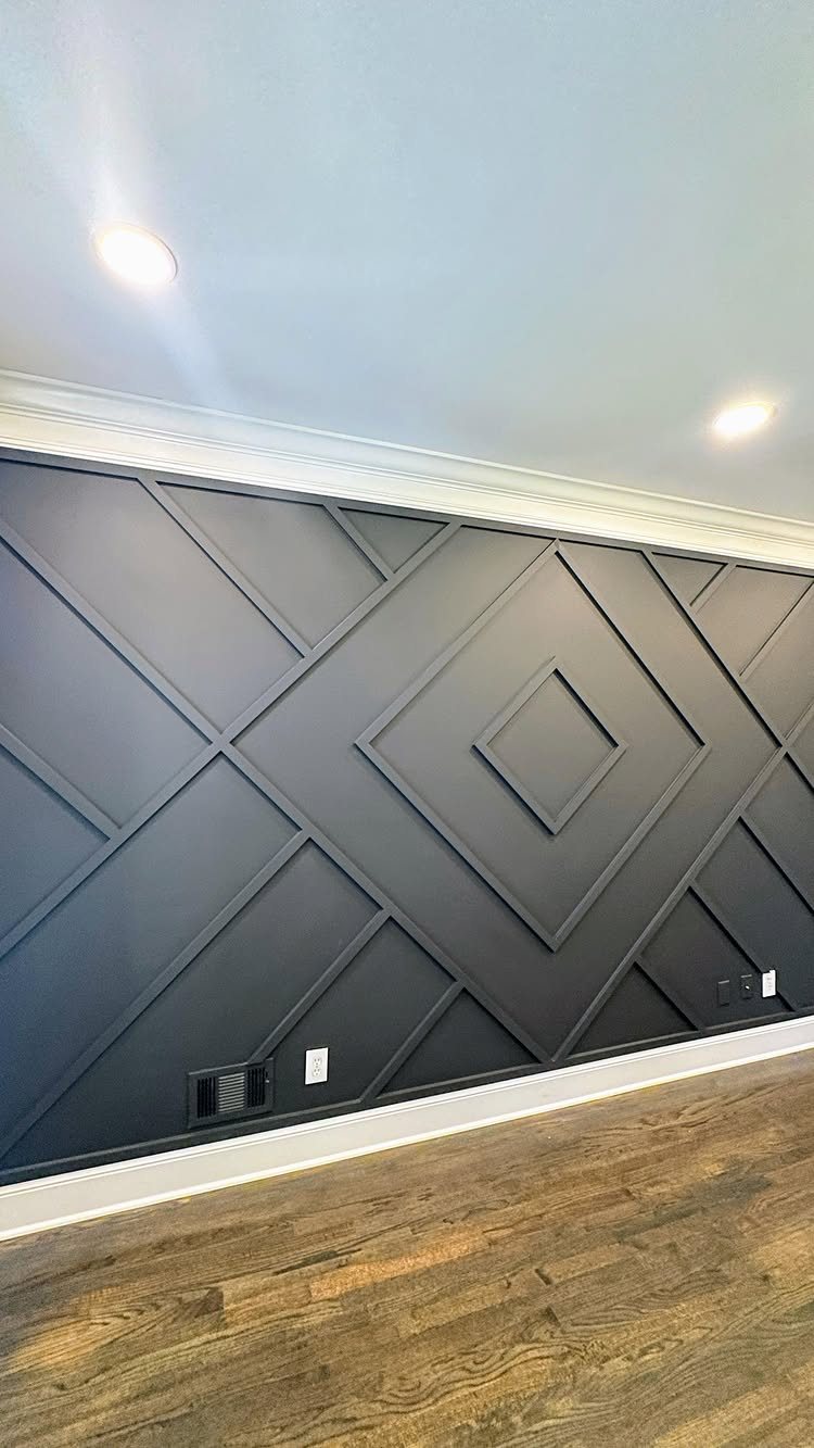Dark geometric paneled accent wall with large diamond patterns and white molding.
