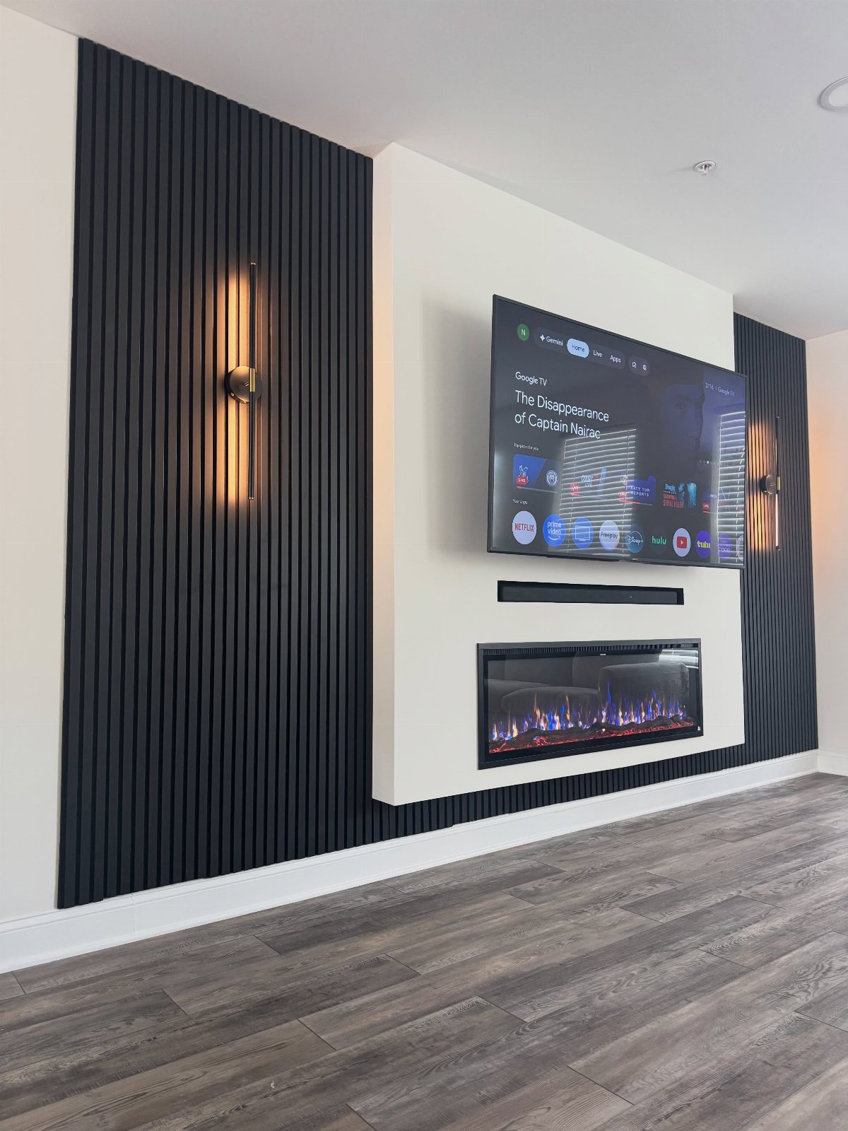 Modern entertainment wall with a television, electric fireplace, and black vertical slat wood paneling.