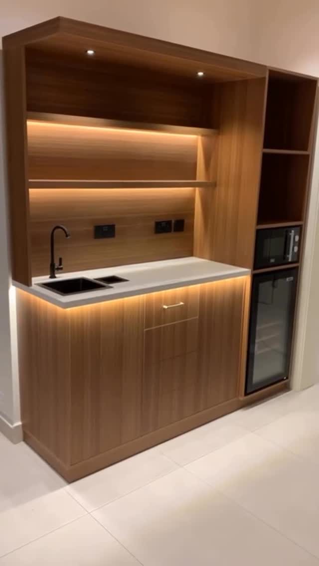 17 Basement Kitchenette Ideas That Maximize Every Square Foot 16 Wooden kitchenette unit with integrated microwave, wine fridge, sink, and warm LED lighting.