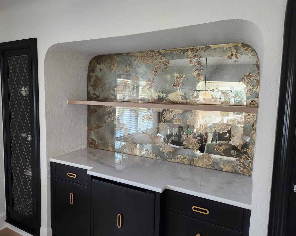 17 Basement Kitchenette Ideas That Maximize Every Square Foot 5 A kitchenette featuring black cabinets, white marble countertop, and a decorative antiqued mirrored backsplash.