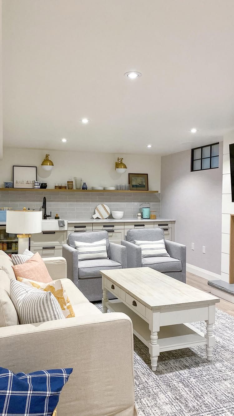 17 Basement Kitchenette Ideas That Maximize Every Square Foot 8 White cabinetry and open shelving arranged in a one-wall kitchenette layout behind a living room setup.