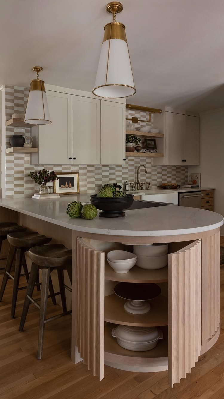 17 Basement Kitchenette Ideas That Maximize Every Square Foot 3 A curved white marble kitchen island with light wood fluted paneling and bar stools.