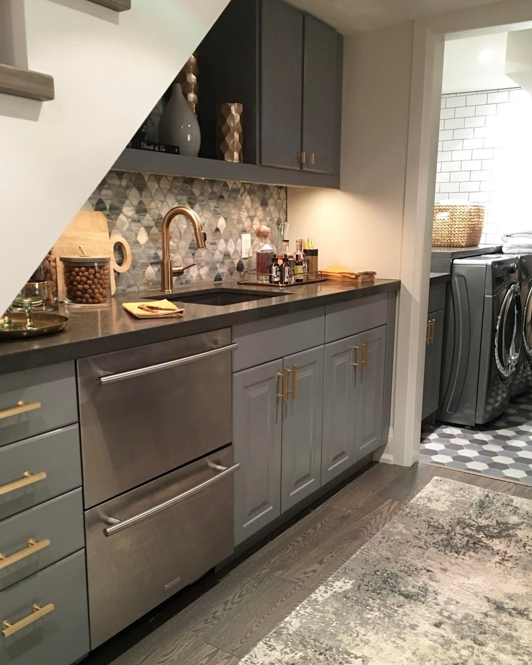 17 Basement Kitchenette Ideas That Maximize Every Square Foot 9 A compact kitchenette with grey cabinets and gold hardware installed under a staircase.
