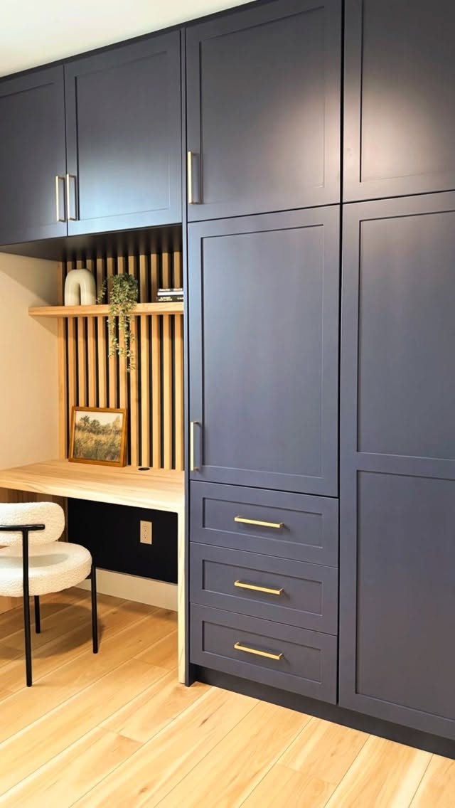 20 Bedroom Office Ideas for Small Spaces and Dual-Purpose Rooms 6 Built-in dark blue cabinetry and drawers surrounding a light wood desk and shelving unit.