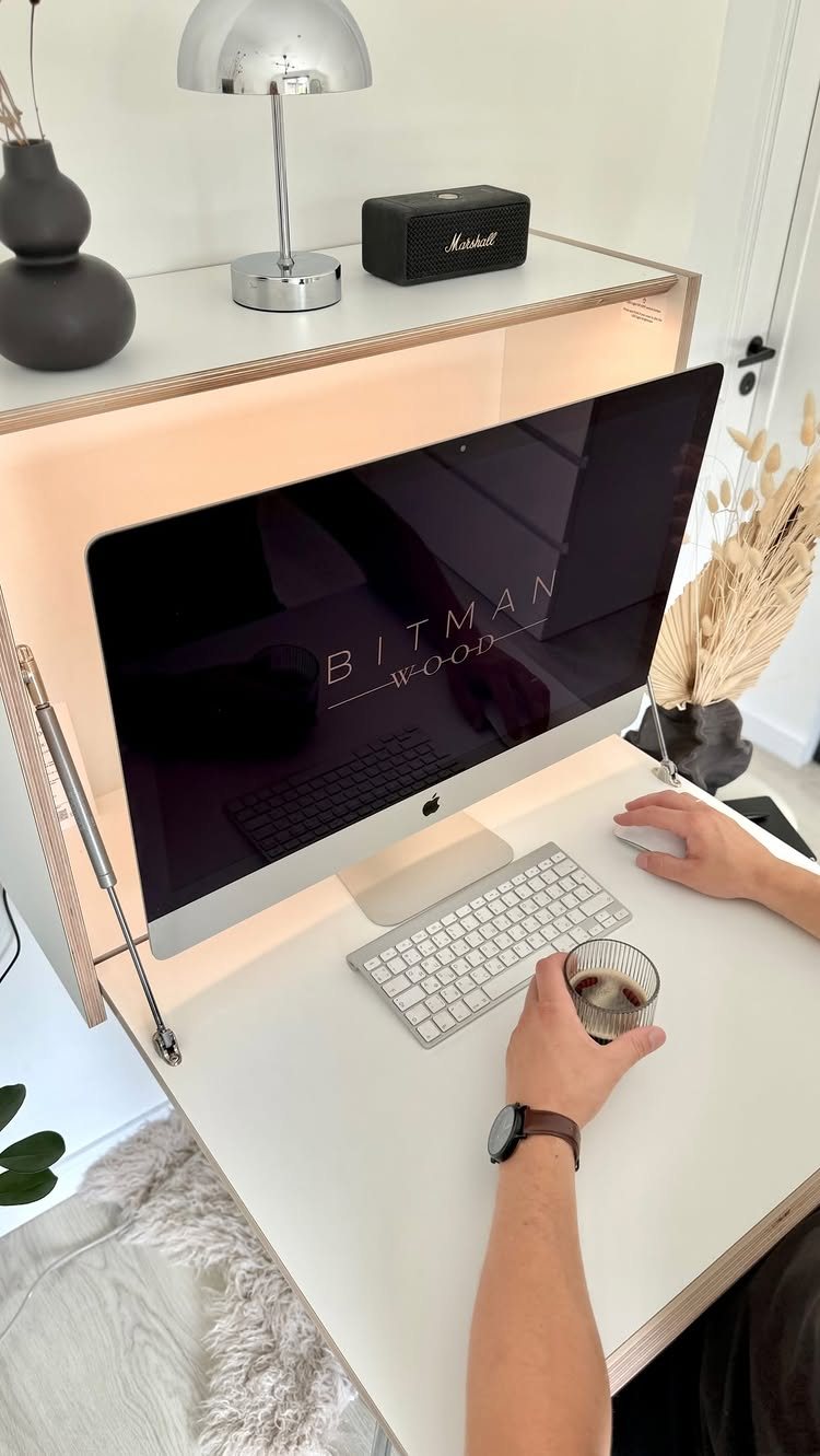 20 Bedroom Office Ideas for Small Spaces and Dual-Purpose Rooms 12 A person using a white wall-mounted desk with a large computer monitor and keyboard.