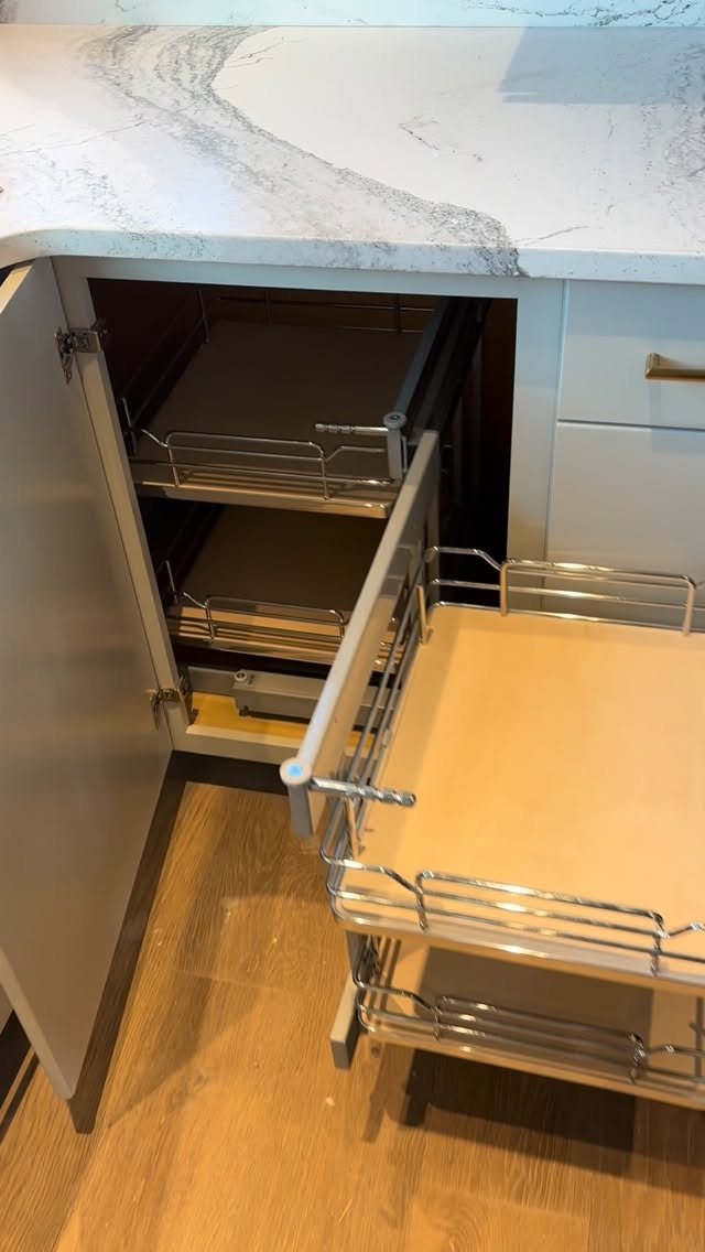 8 Corner Cabinet Ideas for Kitchens That Actually Work 3 Metal wire pull-out shelves installed inside an open kitchen corner cabinet with marble countertop.
