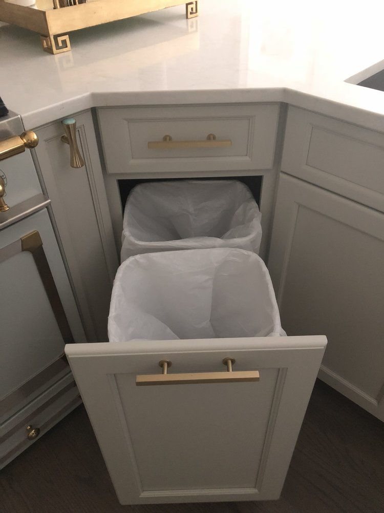 8 Corner Cabinet Ideas for Kitchens That Actually Work 8 An open grey corner cabinet pull-out containing two white trash bags in a kitchen.