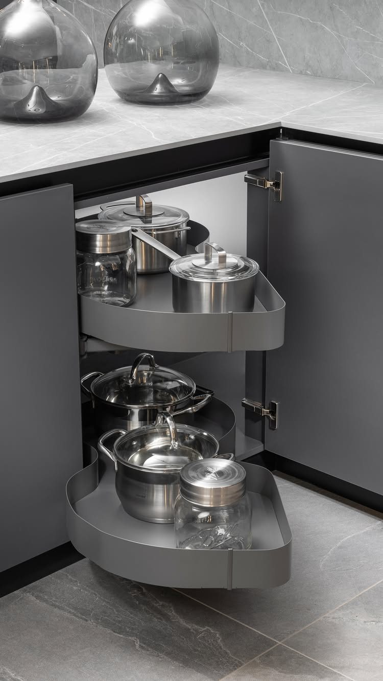 8 Corner Cabinet Ideas for Kitchens That Actually Work 4 Two grey tiered trays holding stainless steel pots and glass jars inside a corner cabinet.