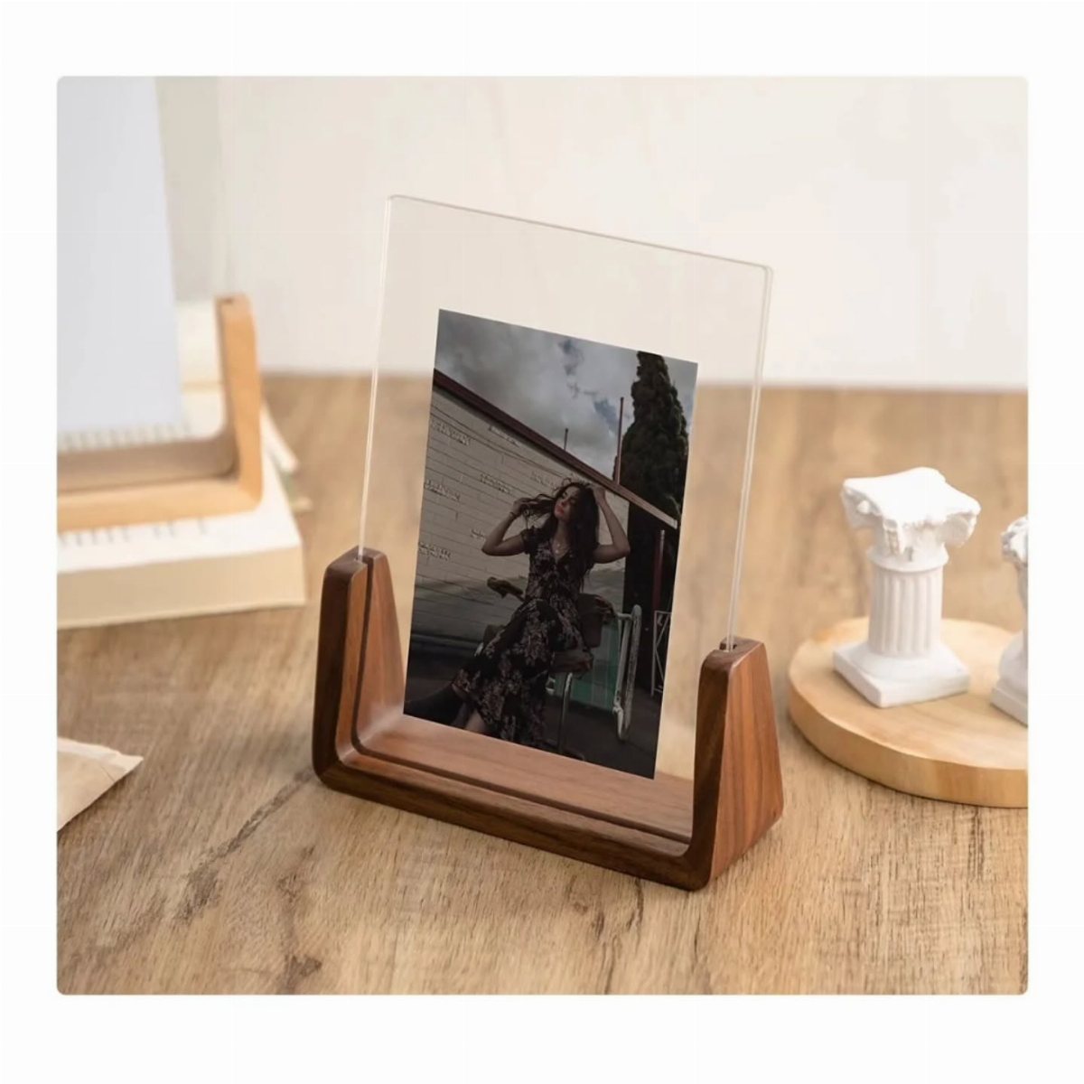 A clear acrylic photo frame with a wooden base displaying a black and white photograph.