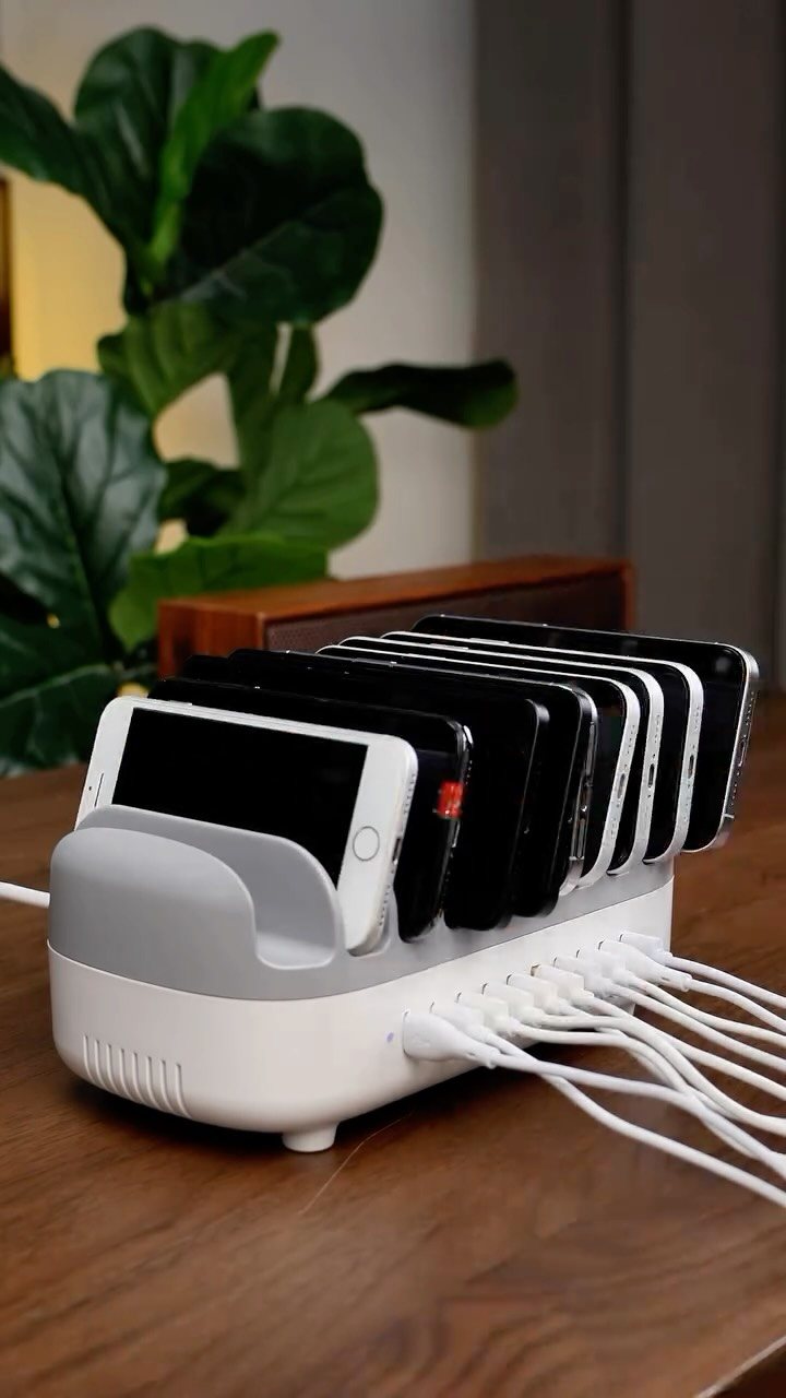 11 Desk Organization Ideas That Tidy Your Space for 2026 11 A white multi-device charging station holding several smartphones on a wooden desk surface.