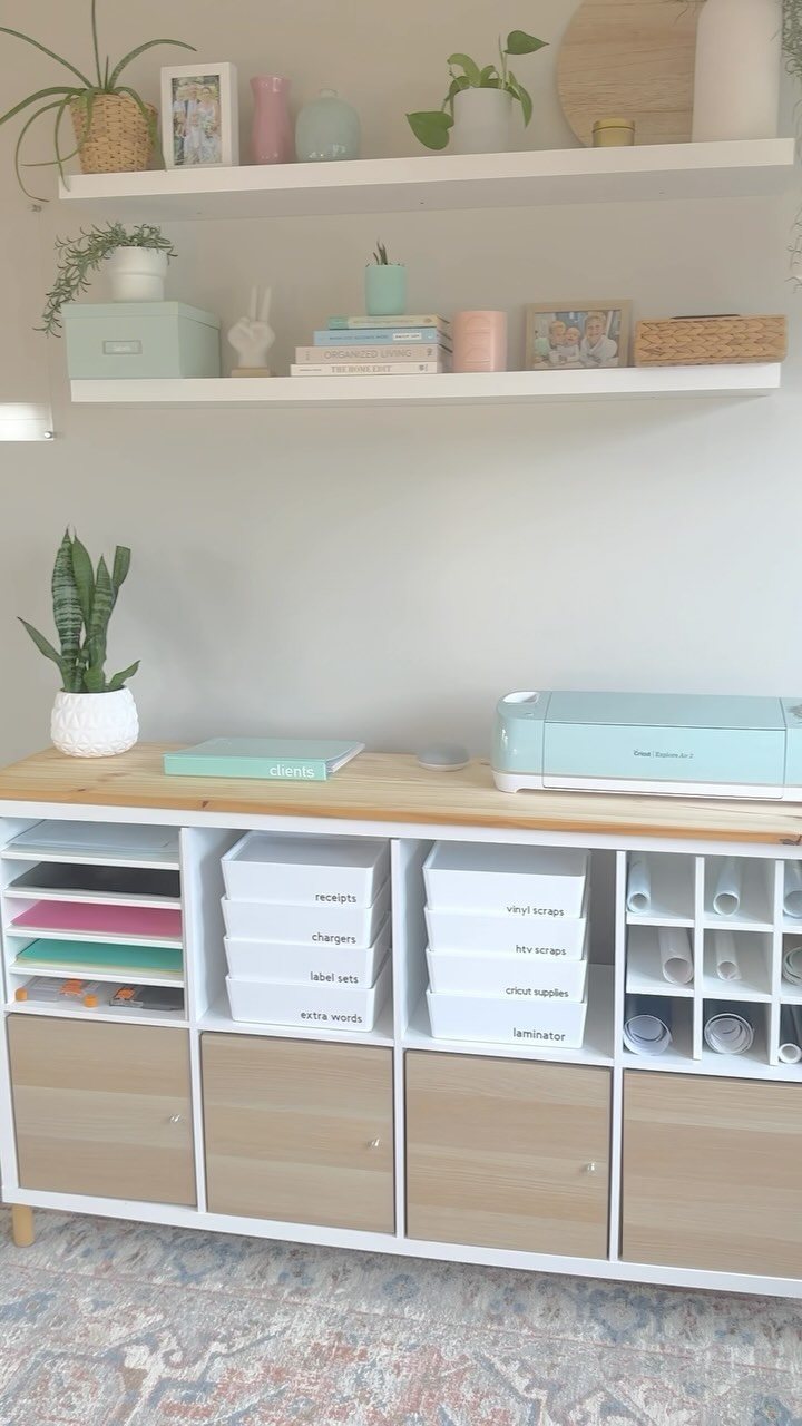 Organized white storage cubbies with labeled bins and colorful folders under a light wood desk surface.