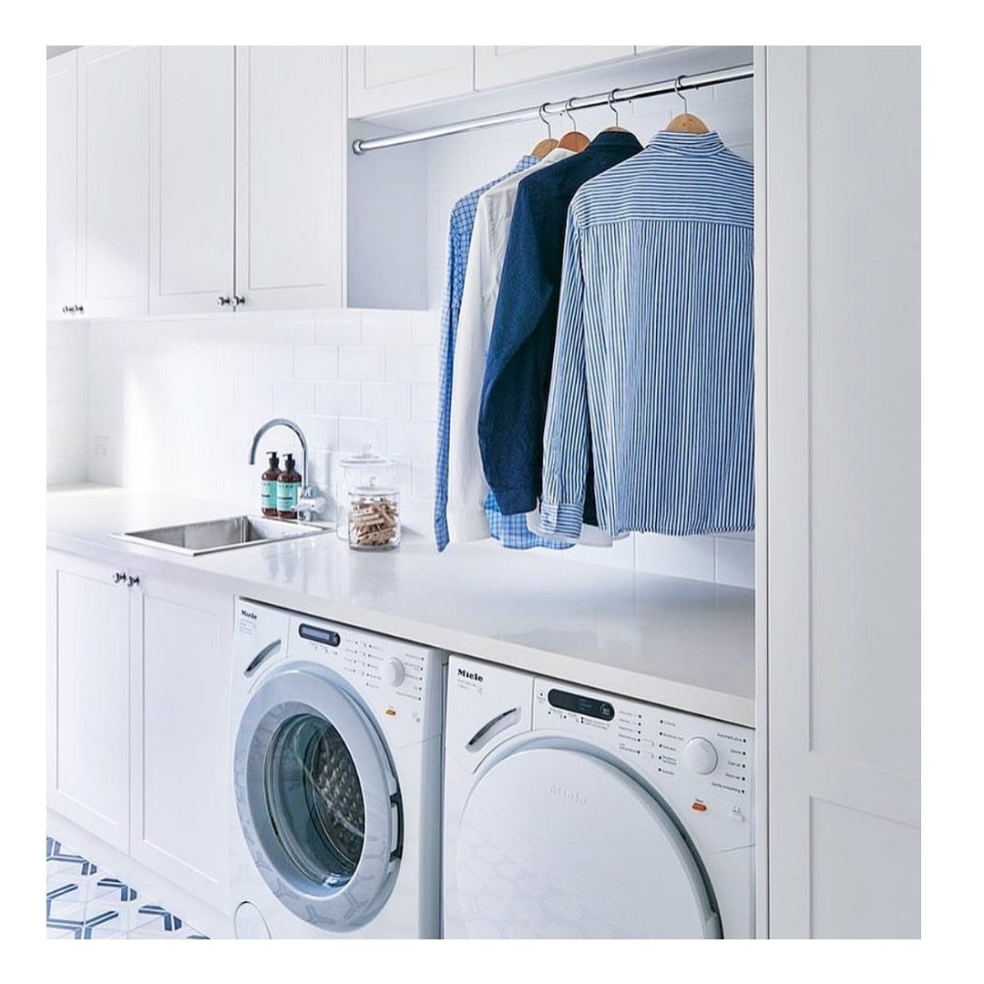 17 Laundry Room Ideas for Storage, Style and Smarter Layouts 14 Blue and white shirts hanging on a silver rod above a white laundry room countertop.