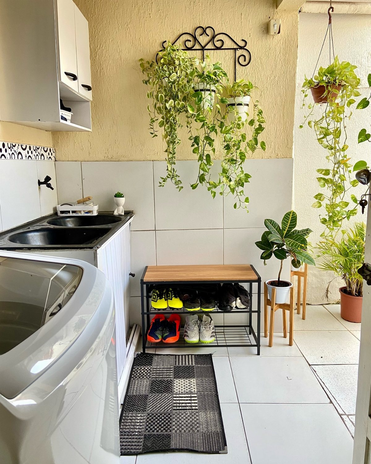 17 Laundry Room Ideas for Storage, Style and Smarter Layouts 9 Green trailing plants hanging from a black metal wall rack in a laundry room.