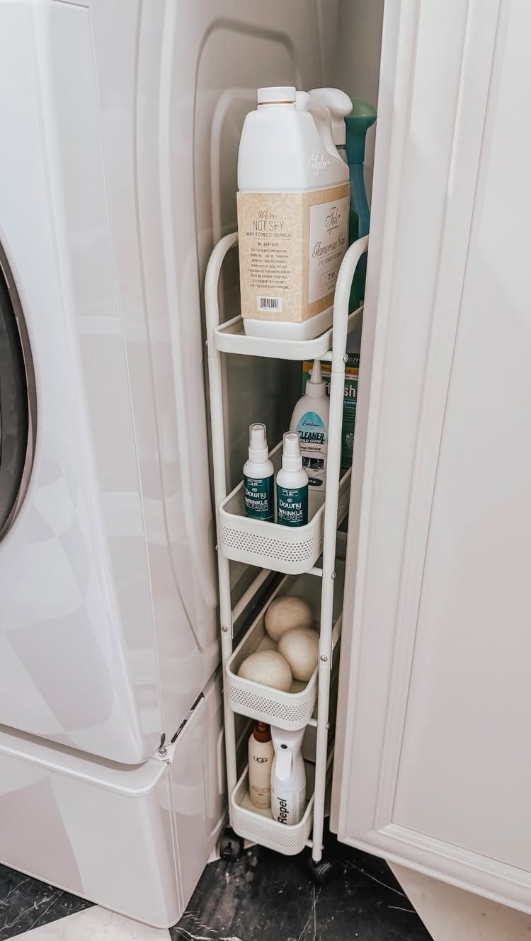 17 Laundry Room Ideas for Storage, Style and Smarter Layouts 1 A slim white rolling storage cart filled with cleaning supplies tucked between a washing machine and cabinet.