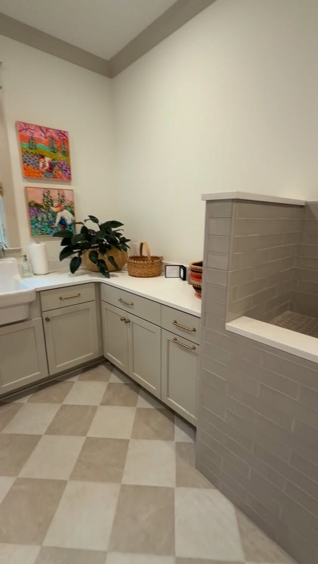 17 Laundry Room Ideas for Storage, Style and Smarter Layouts 12 Two colorful art pieces hanging on a white wall above a laundry room countertop.