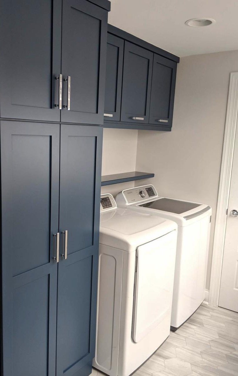 17 Laundry Room Ideas for Storage, Style and Smarter Layouts 10 Dark blue laundry room cabinets with silver hardware next to white washing machines.