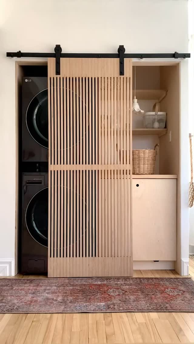 17 Laundry Room Ideas for Storage, Style and Smarter Layouts 13 A light wood slatted sliding barn door partially concealing a laundry nook with stacked machines.