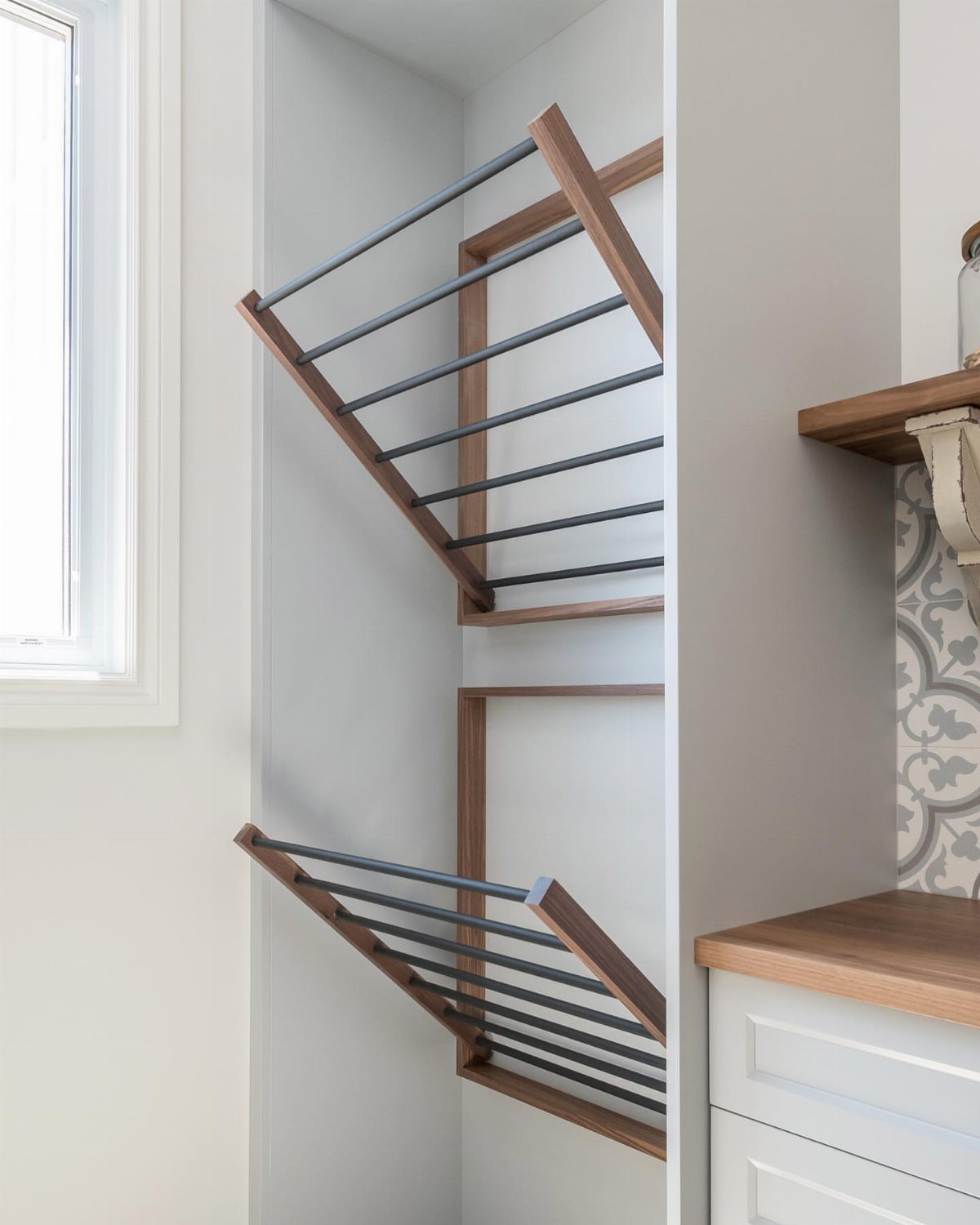 17 Laundry Room Ideas for Storage, Style and Smarter Layouts 7 Two wooden wall-mounted drying racks with black metal bars extended from a white wall.