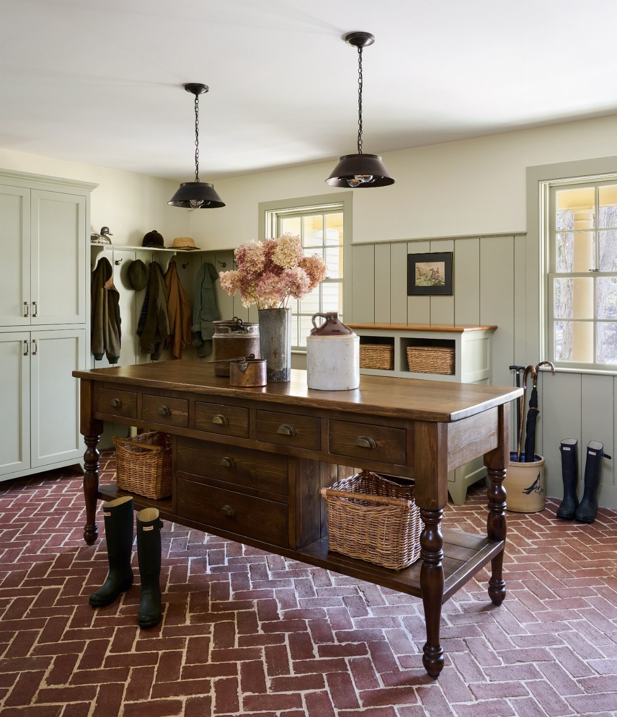 17 Mudroom Ideas for Entryways That Actually Work in 2026 10 A large wooden multifunctional island with drawers and baskets in a mudroom.