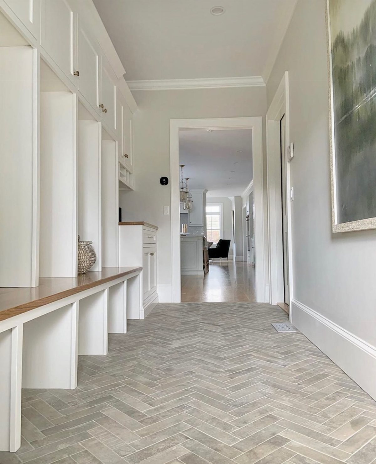 17 Mudroom Ideas for Entryways That Actually Work in 2026 17 Herringbone patterned grey tile flooring in a bright mudroom with white built-in cabinetry.