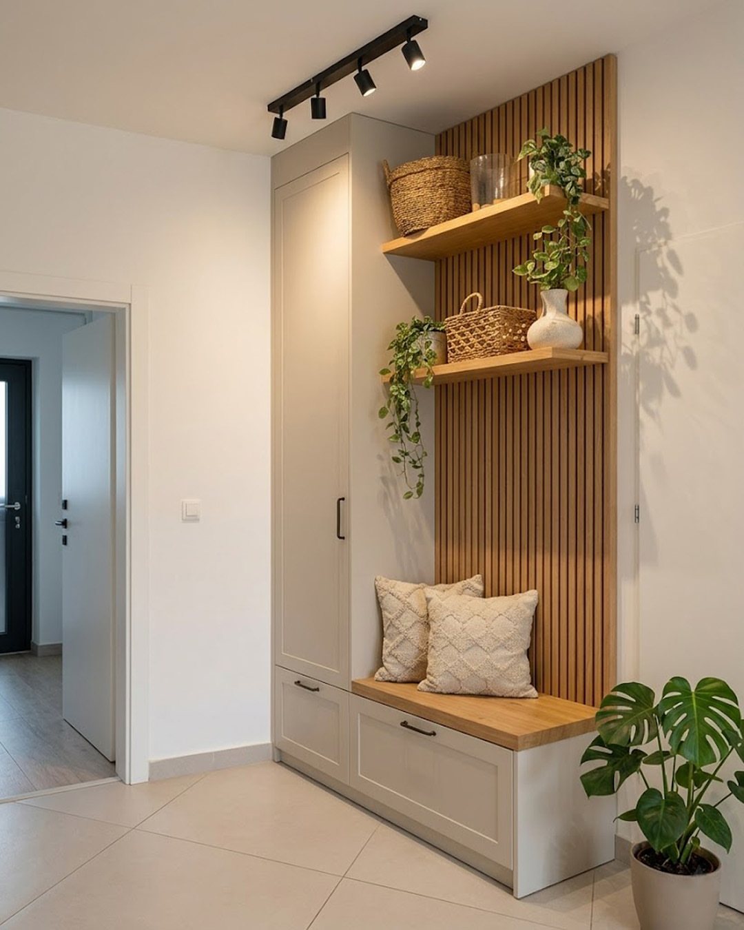 17 Mudroom Ideas for Entryways That Actually Work in 2026 5 Built-in mudroom unit with wooden open shelves, a bench seat, and decorative plants on a slat wall.