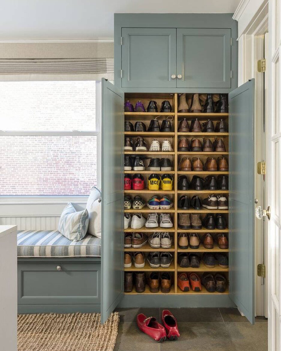 17 Mudroom Ideas for Entryways That Actually Work in 2026 3 Built-in light blue cabinet with open doors revealing organized wooden shelves filled with many pairs of shoes.