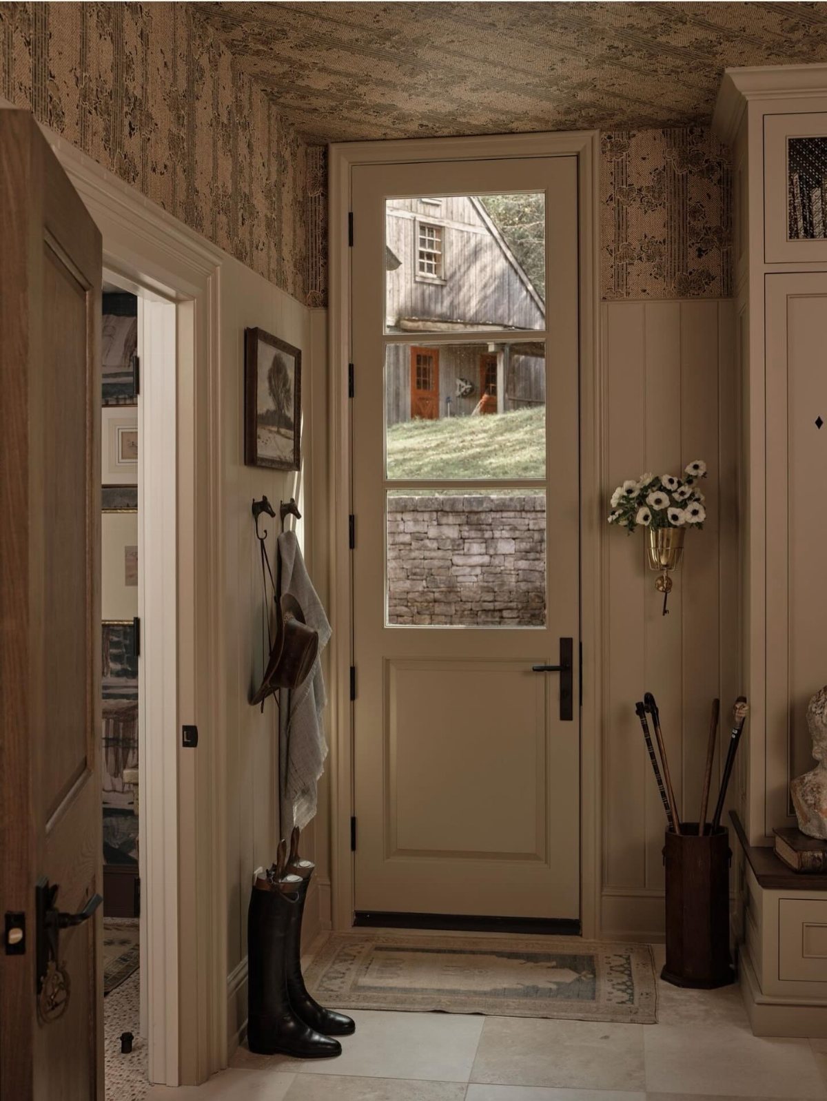 17 Mudroom Ideas for Entryways That Actually Work in 2026 2 Metal wall-mounted hooks holding a bag and clothing in a rustic mudroom entryway.