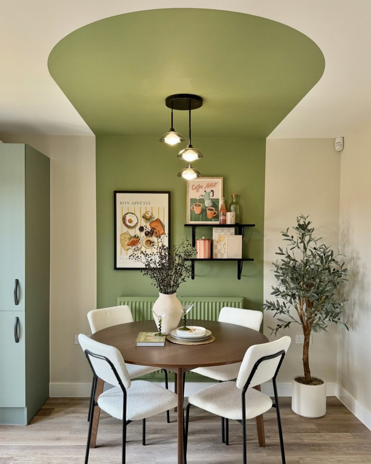 Sage green painted alcove with curved ceiling defining a dining area zone.